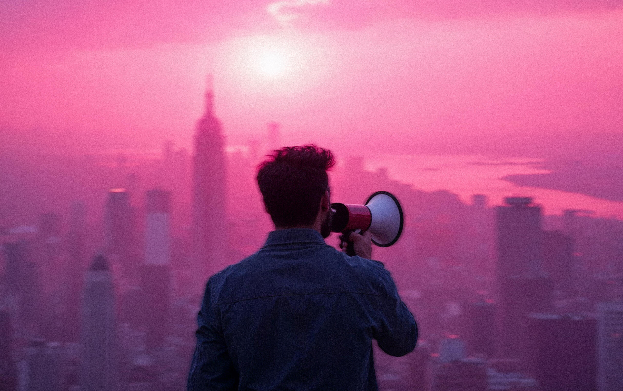 Man holding a megaphone stands before a city